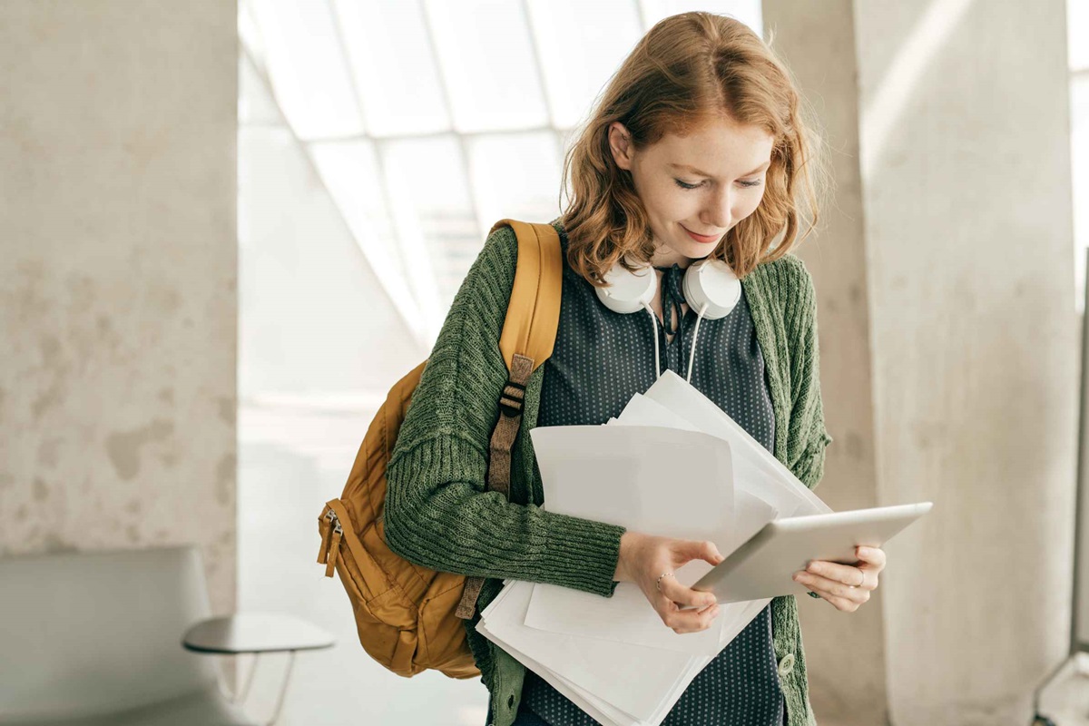 Young lady with headphones, inspecting documents for her student visa document checklist